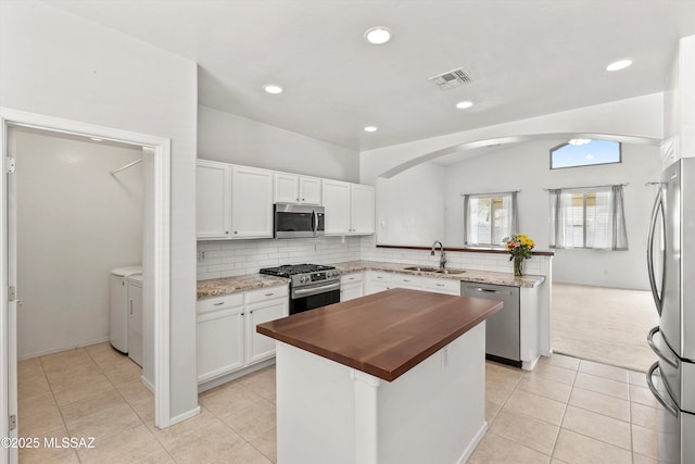 5523 W Carriage Dr, Tucson, AZ 85742 - kitchen with appliances with stainless steel finishes, washing machine and dryer, butcher block countertops, a sink, and white cabinetry