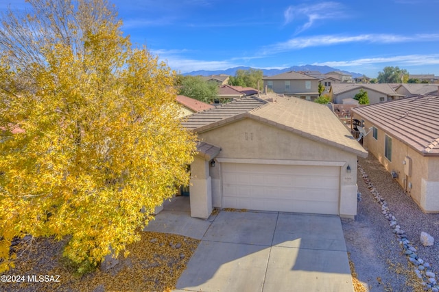 9284 N Red Diamond Ave, Tucson, AZ 85742 - view of front of home with stucco siding, an attached garage, concrete driveway, a residential view, and a mountain view