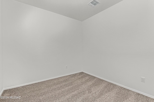 carpeted spare room featuring baseboards, lofted ceiling, and visible vents