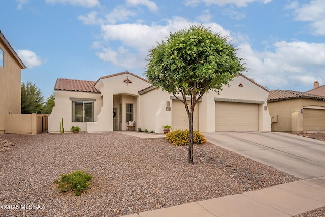 mediterranean / spanish-style house with a tiled roof, stucco siding, concrete driveway, an attached garage, and fence