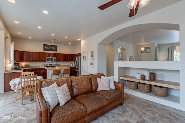 living room with arched walkways, a ceiling fan, recessed lighting, and baseboards