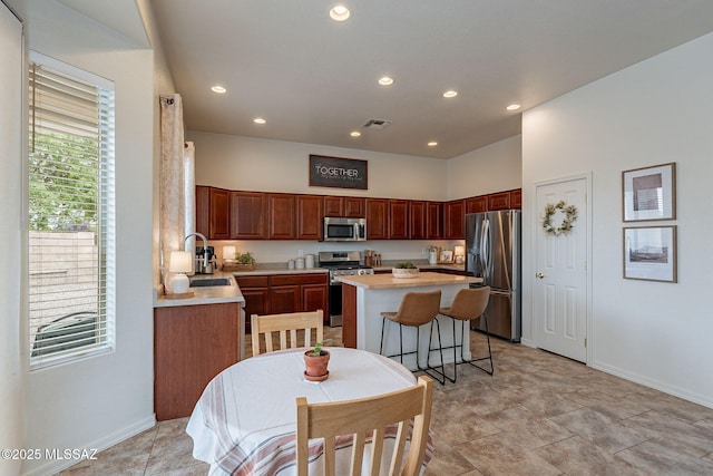 kitchen featuring stainless steel appliances, a sink, a kitchen island, light countertops, and recessed lighting