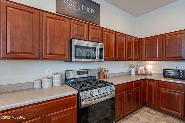 kitchen featuring appliances with stainless steel finishes, light countertops, and brown cabinets