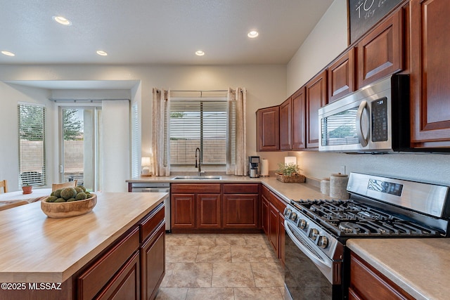 kitchen featuring stainless steel appliances, a sink, butcher block counters, and recessed lighting