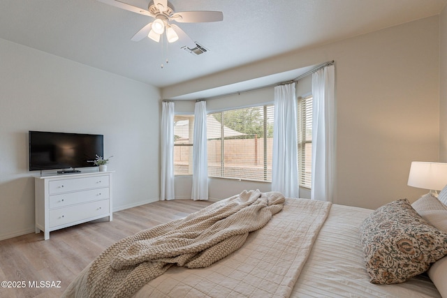 bedroom with light wood-type flooring, baseboards, and a ceiling fan