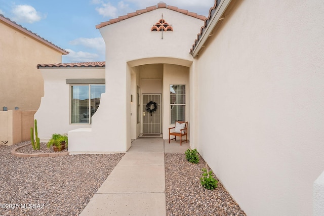 property entrance with stucco siding and a tile roof