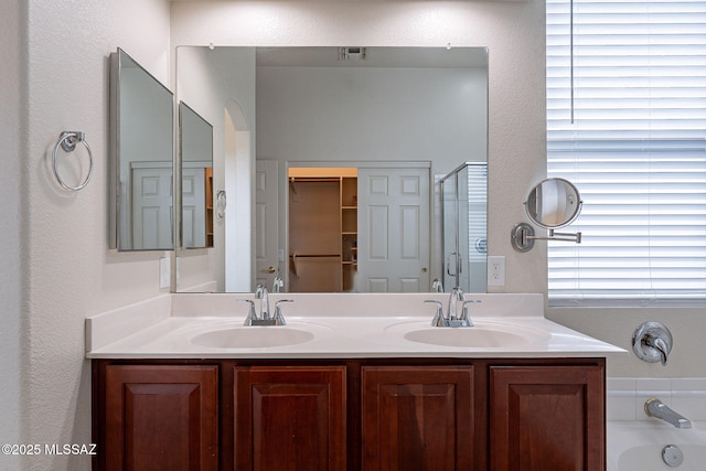 full bath with a shower stall, double vanity, a tub, and a textured wall