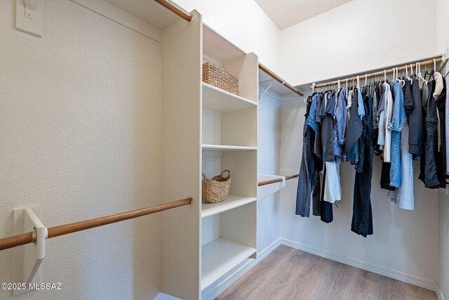 walk in closet with wood finished floors