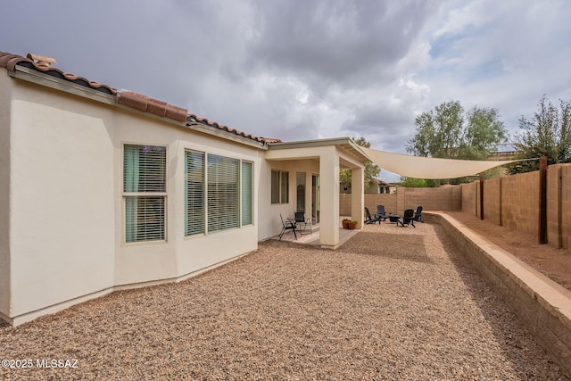 back of house with stucco siding, a fenced backyard, a patio area, and a tiled roof