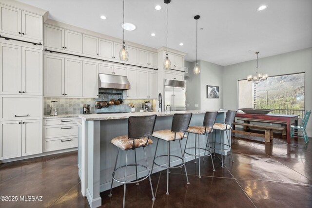 6695 W Banded Gecko Way, Tucson, AZ 85745 - kitchen with built in fridge, concrete flooring, under cabinet range hood, decorative backsplash, and recessed lighting
