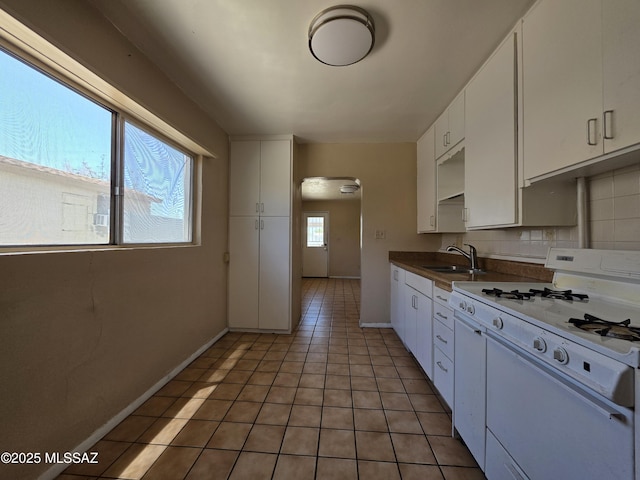 3638 S Bronson Ave, Tucson, AZ 85713 - kitchen with white gas range, arched walkways, a sink, white cabinets, and light tile patterned flooring
