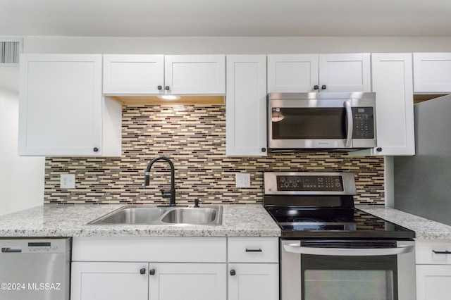 4029 E Fort Lowell Rd, Tucson, AZ 85712 - kitchen featuring appliances with stainless steel finishes, a sink, white cabinets, and backsplash
