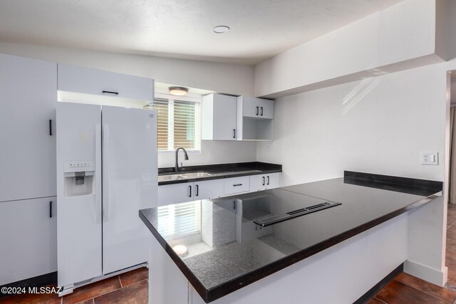 4367 N Radin Ave, Tucson, AZ 85705 - kitchen with dark countertops, white cabinets, white refrigerator with ice dispenser, and a sink