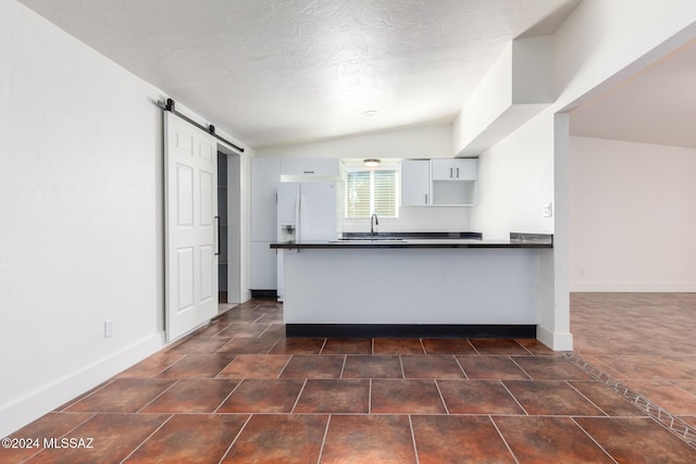 4367 N Radin Ave, Tucson, AZ 85705 - kitchen featuring a barn door, a sink, a peninsula, dark countertops, and white cabinets