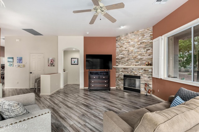 1497 W Carmel Pointe Dr, Oro Valley, AZ 85737 - living room with arched walkways, a ceiling fan, wood finished floors, a stone fireplace, and baseboards