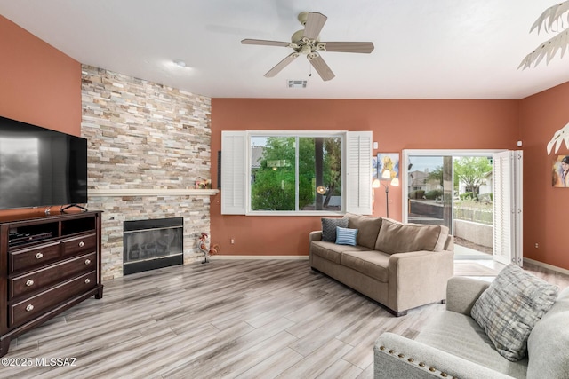 1497 W Carmel Pointe Dr, Oro Valley, AZ 85737 - living room with light wood finished floors, a ceiling fan, a stone fireplace, and baseboards