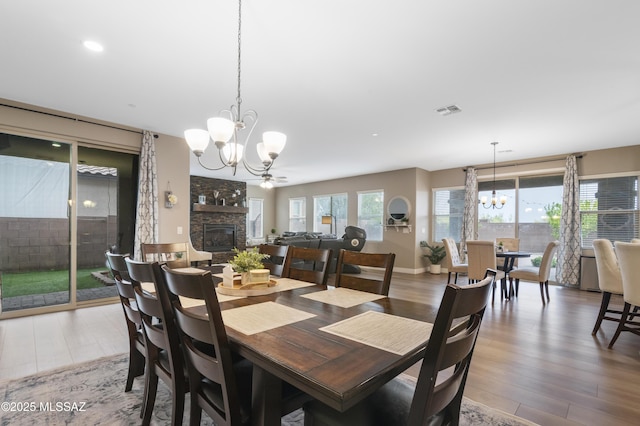 3443 W Tailfeather Dr, Marana, AZ 85658 - dining space with a chandelier, a stone fireplace, and wood finished floors