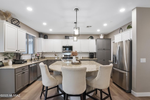 3443 W Tailfeather Dr, Marana, AZ 85658 - kitchen featuring appliances with stainless steel finishes, gray cabinets, a kitchen island, a sink, and light wood-type flooring