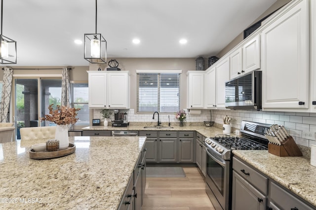 3443 W Tailfeather Dr, Marana, AZ 85658 - kitchen with stainless steel appliances, gray cabinets, a sink, light wood-style flooring, and decorative backsplash