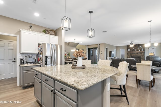 3443 W Tailfeather Dr, Marana, AZ 85658 - kitchen featuring stainless steel fridge with ice dispenser, gray cabinetry, light wood-type flooring, a kitchen island, and a breakfast bar