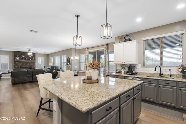3443 W Tailfeather Dr, Marana, AZ 85658 - kitchen featuring gray cabinetry, a sink, a kitchen island, white cabinets, and light wood-style floors