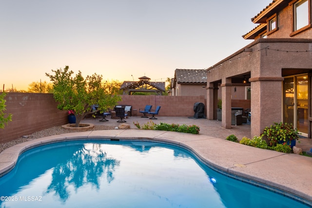 3443 W Tailfeather Dr, Marana, AZ 85658 - pool at dusk featuring a patio area and a fenced backyard