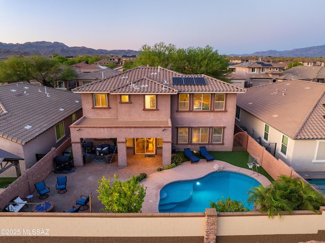 3443 W Tailfeather Dr, Marana, AZ 85658 - back of property with a fenced backyard, roof mounted solar panels, stucco siding, and a mountain view