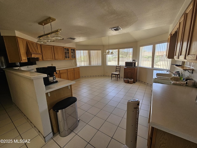 1760 W Airport Rd, Willcox, AZ 85643 - kitchen featuring a chandelier, a sink, a textured ceiling, light tile patterned floors, and brown cabinetry