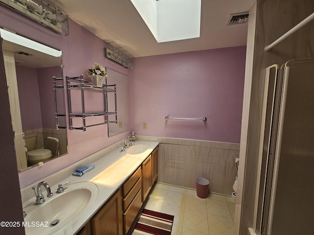 1760 W Airport Rd, Willcox, AZ 85643 - full bathroom featuring toilet, a skylight, double vanity, a wainscoted wall, and a shower