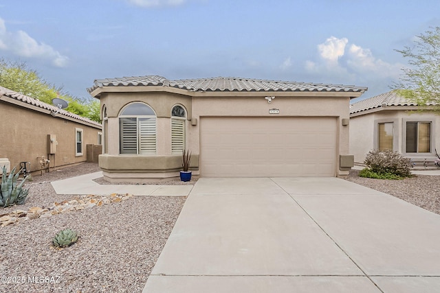 mediterranean / spanish-style home with concrete driveway, an attached garage, a tiled roof, and stucco siding
