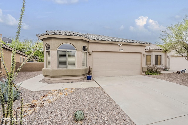 mediterranean / spanish house featuring a garage, a tiled roof, concrete driveway, stucco siding, and fence