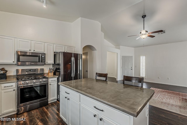 kitchen featuring appliances with stainless steel finishes, vaulted ceiling, ceiling fan, arched walkways, and dark wood finished floors