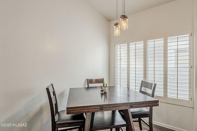 dining space with vaulted ceiling, wood finished floors, and baseboards