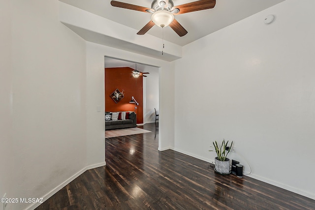 empty room featuring ceiling fan, wood finished floors, a smoke detector, and baseboards
