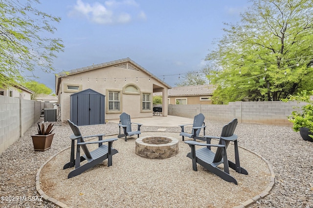 rear view of house featuring a fire pit, a fenced backyard, a storage unit, a patio, and an outdoor structure