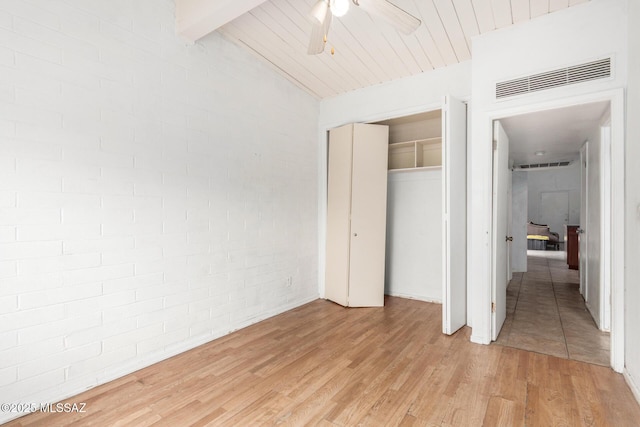 unfurnished bedroom featuring light wood-style floors, a closet, brick wall, and ceiling fan