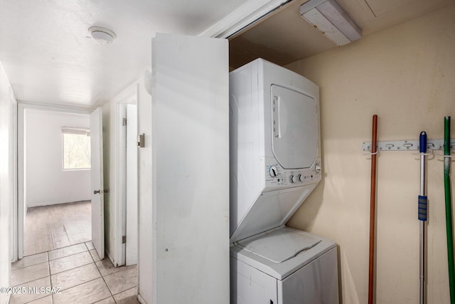 laundry area featuring stacked washing machine and dryer and light tile patterned floors