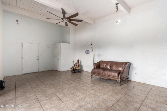 living area featuring a ceiling fan, beamed ceiling, light tile patterned floors, and a towering ceiling
