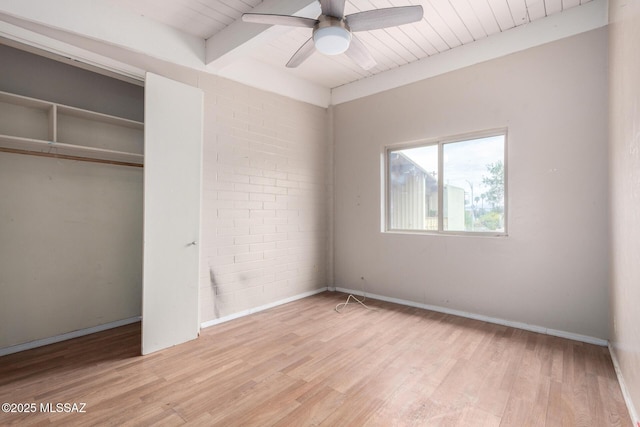 unfurnished bedroom with light wood-style floors, beamed ceiling, wooden ceiling, baseboards, and a closet