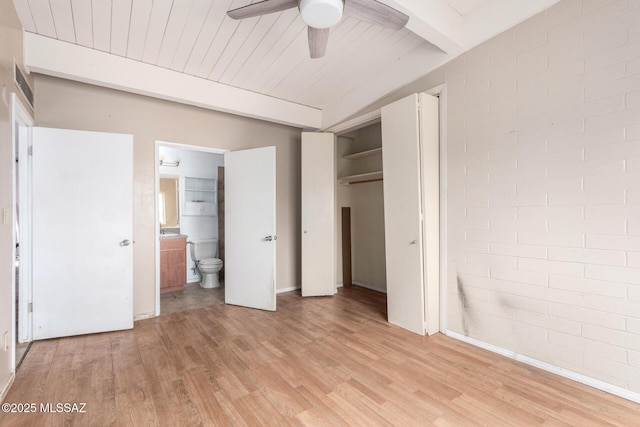 unfurnished bedroom with beamed ceiling, light wood-style floors, connected bathroom, a closet, and wooden ceiling