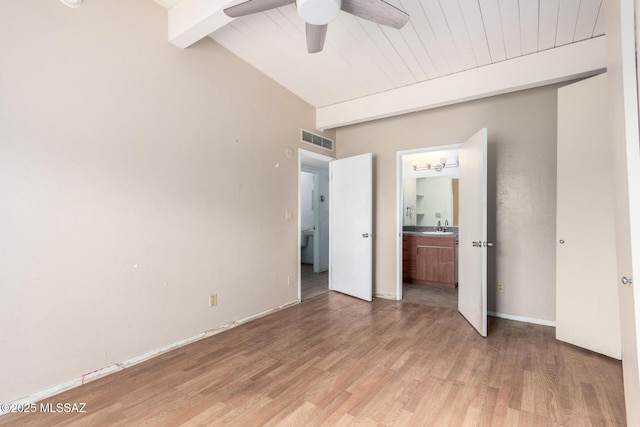 unfurnished bedroom featuring beamed ceiling, light wood-style floors, connected bathroom, a sink, and a ceiling fan
