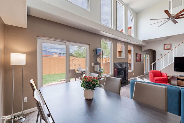 4296 N Rillito Creek Pl, Tucson, AZ 85719 - dining space featuring a fireplace, stairs, baseboards, arched walkways, and high vaulted ceiling