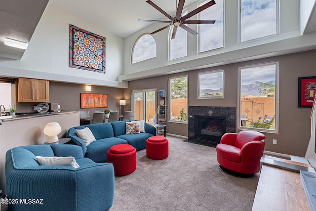 4296 N Rillito Creek Pl, Tucson, AZ 85719 - living room featuring a towering ceiling, a high end fireplace, ceiling fan, carpet flooring, and baseboards