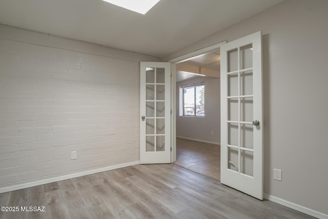 6664 E Mary Dr, Tucson, AZ 85730 - empty room with french doors, baseboards, wood finished floors, and brick wall