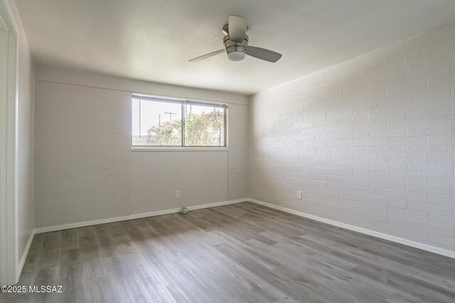 6664 E Mary Dr, Tucson, AZ 85730 - unfurnished room with wood finished floors, brick wall, baseboards, and a ceiling fan