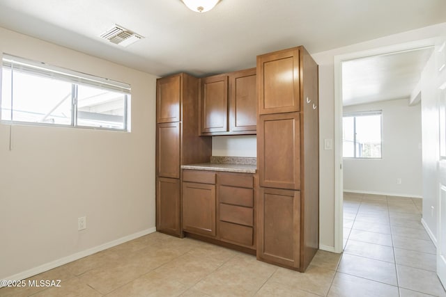 6664 E Mary Dr, Tucson, AZ 85730 - kitchen with light countertops, brown cabinets, light tile patterned floors, and baseboards