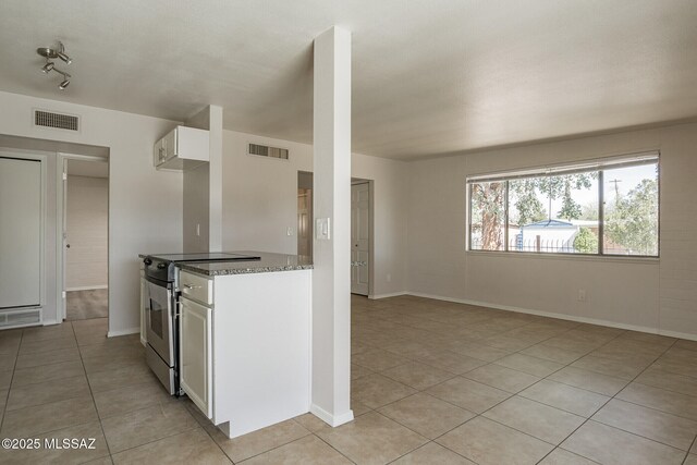 6664 E Mary Dr, Tucson, AZ 85730 - kitchen featuring stainless steel range with electric stovetop, light tile patterned floors, dark stone countertops, white cabinetry, and baseboards