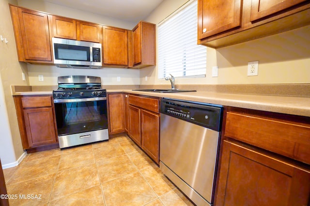 14333 S Camino Vallado, Sahuarita, AZ 85629 - kitchen with stainless steel appliances, brown cabinets, light countertops, a sink, and light tile patterned floors