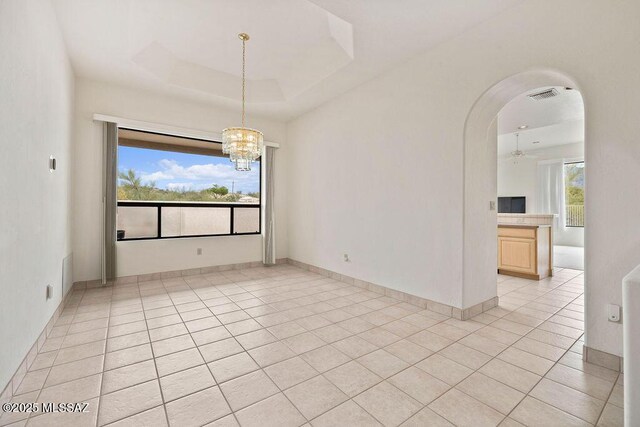 11126 N Guava Dr, Oro Valley, AZ 85737 - empty room featuring arched walkways, light tile patterned floors, and a chandelier