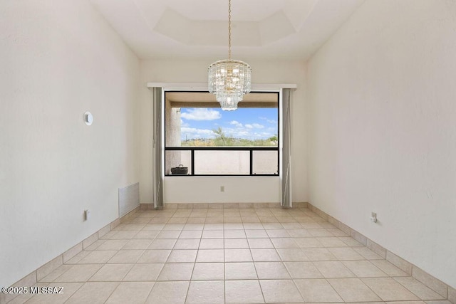 11126 N Guava Dr, Oro Valley, AZ 85737 - empty room featuring a chandelier, light tile patterned flooring, and a raised ceiling